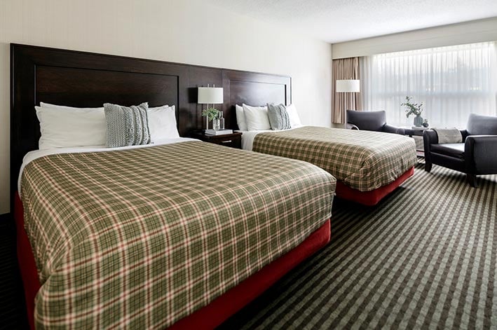 A hotel room with two bed with tartan sheets