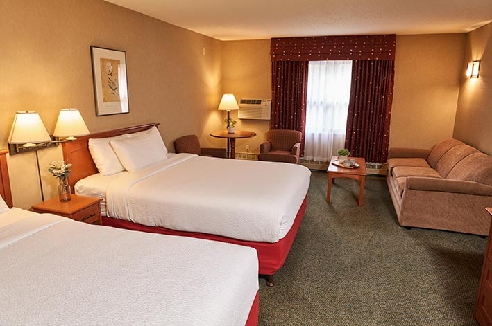 Two beds, a couch and a seating area in a hotel room