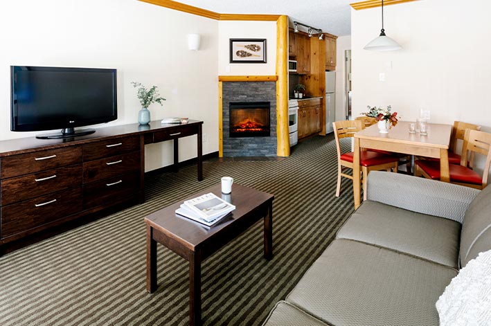 A living area in a hotel room with coffee table and fireplace.