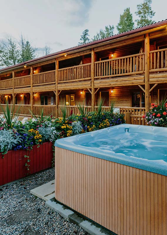 A hot tub and a flower bed sits in front of the cabin exterior.