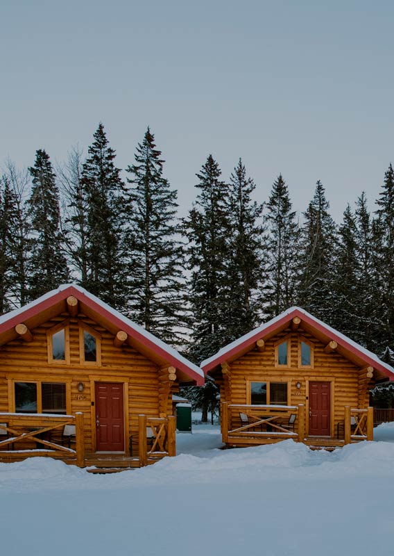 Wooden cabins with red roofs covered in snow.