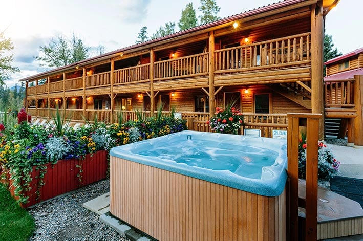 A hot tub outside of a two-story lodge building.