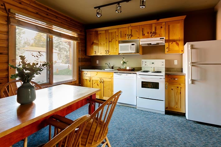 The kitchen inside a wooden cabin with a table and chairs.