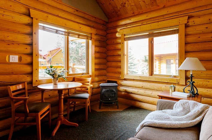 A wooden cabin living room with table and sofa.