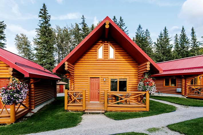 A wooden cabin with a red roof decorated with hanging flowers