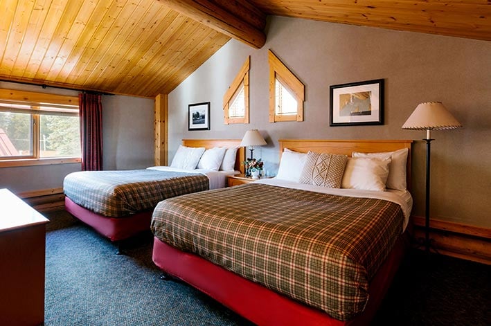 Two beds in a log cabin room