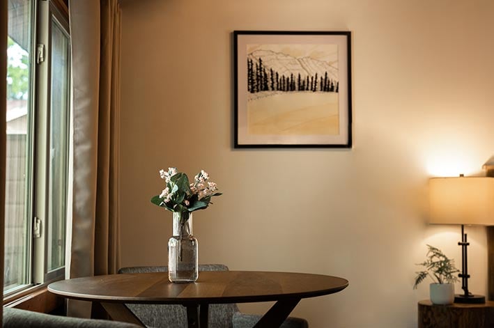 Small dining table in a hotel room with a window to its left