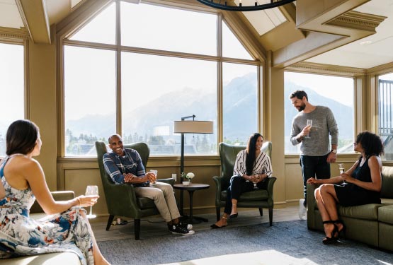 A group of friends sit in a lounge overlooking a small town.