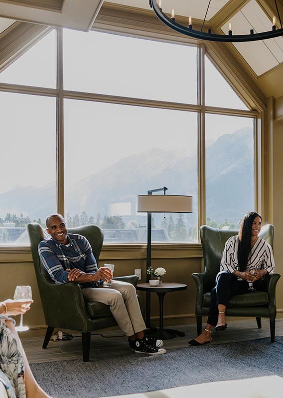 A group of people sit in a lounge with a big window to a mountain view.