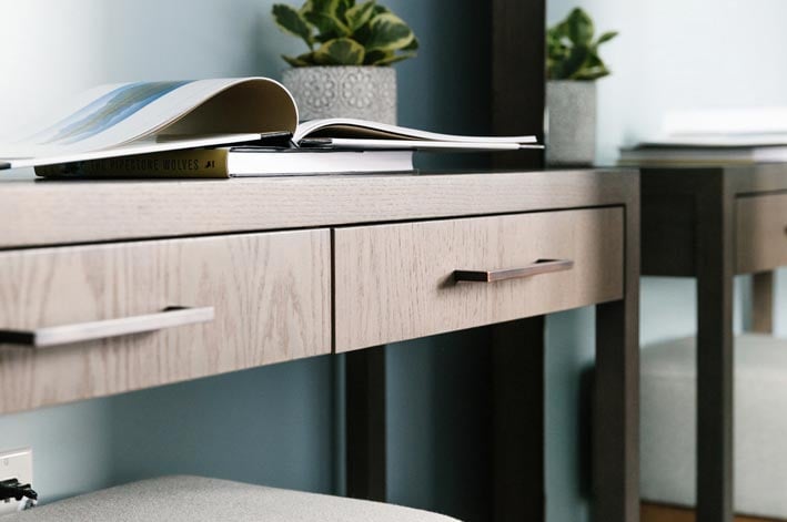 A close-up view of desk drawers with books and a plant on top.