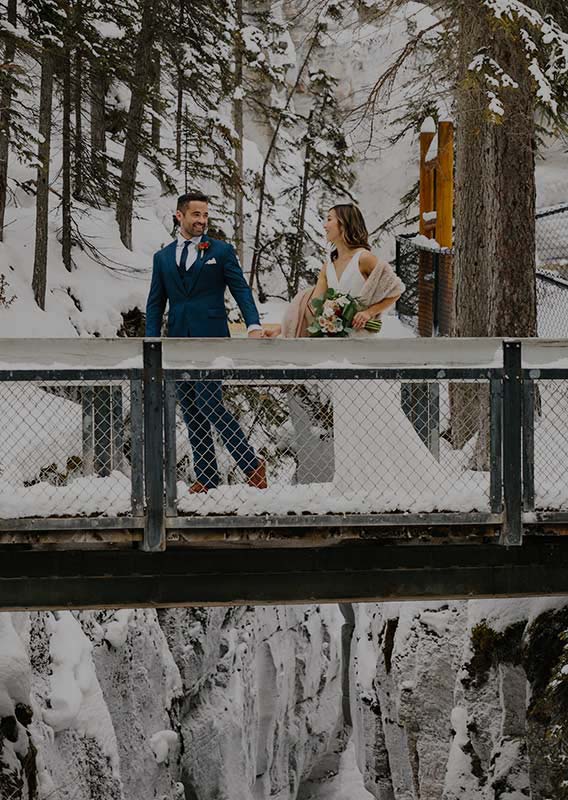 A couple walk across a bridge over Maligne Canyon in the winter