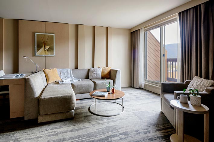 A hotel living room with chairs, fireplace and television