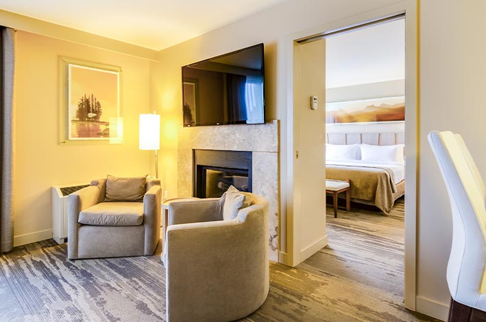 A hotel living room with television above a fireplace.