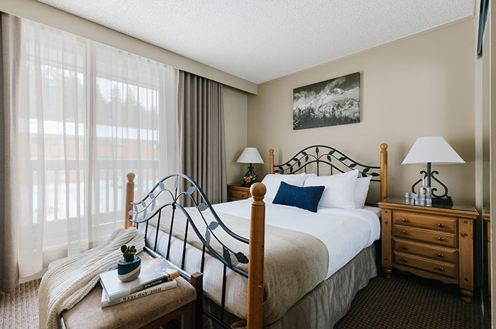 A hotel room bedroom with a king bed and sliding door balcony