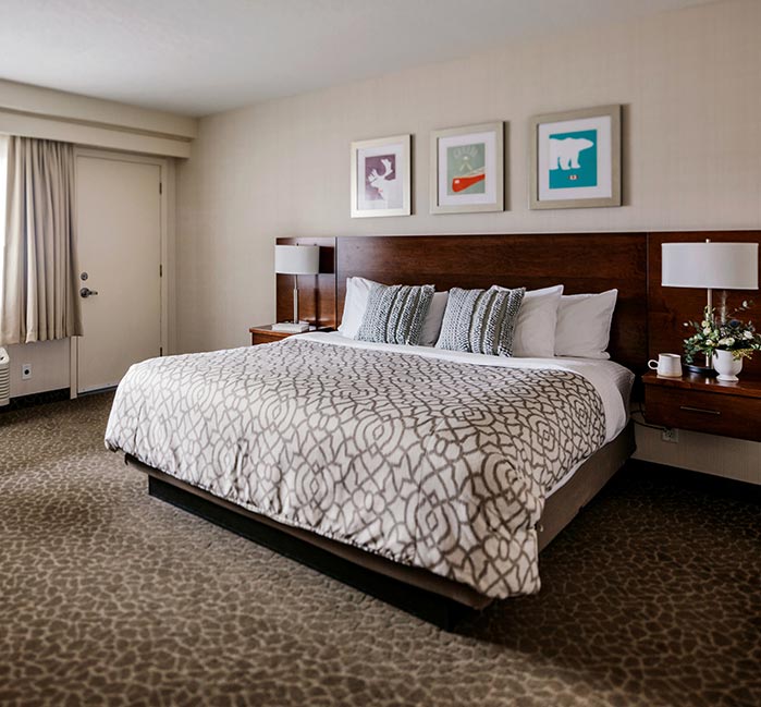 A king bed in a hotel room with modern decor.