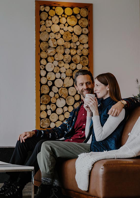 Two people sit in a leather sofa in a rustic-modern hotel lobby