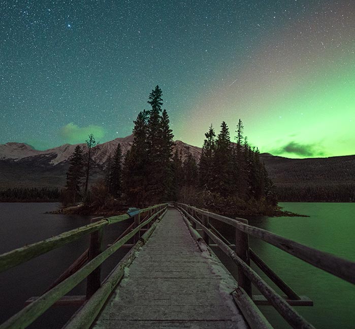 Pyramid Lake Island at night with green aurora borealis in the sky