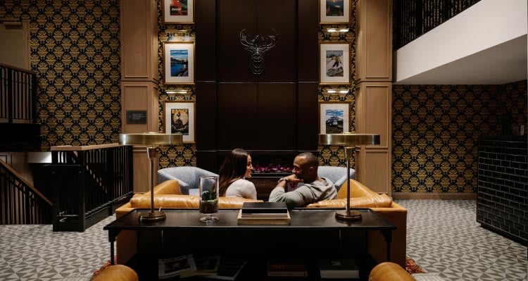 The lobby of the Mount Royal Hotel, with historic tourism posters and modern art above a fireplace.