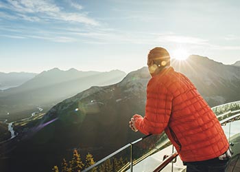 A man leans against the fence of the Banff Gondola at Sunset.