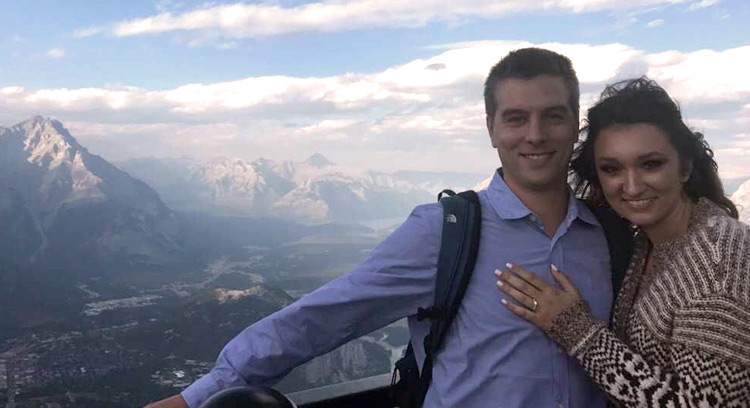 Newly-engaged couple at the top of Sulphur Mountain looking over the town of Banff