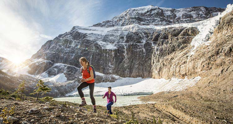 Two women hike in a rocky alpine bowl.