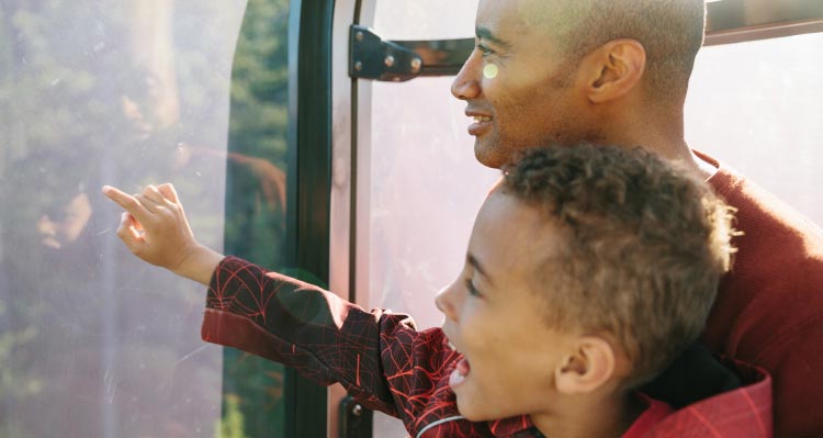 A father and son look out a Banff Gondola cabin.