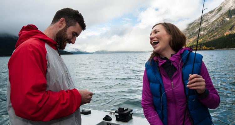 Two people get fishing rods ready on a boat.