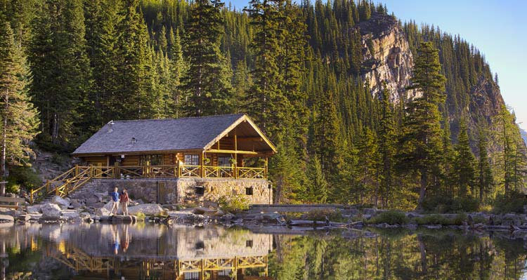 A wooden and stone teahouse nestled between trees and a lake.