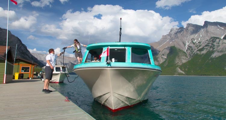 Two boat-workers get a blue and white boat ready to dock.