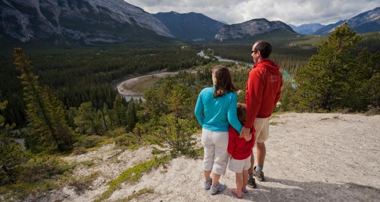 A family stands atop a rocky outcropping over a wide valley.