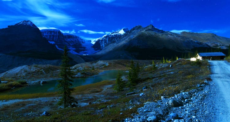 A gravel road leads to the water treatment plant at the Columbia Icefield Discovery Centre. Ice-capped peaks tower in the distance.