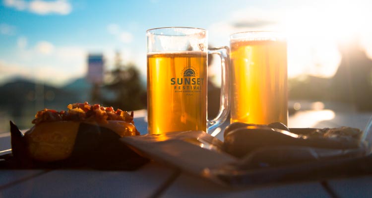 Two glasses of beer with snacks glow in the sunlight.