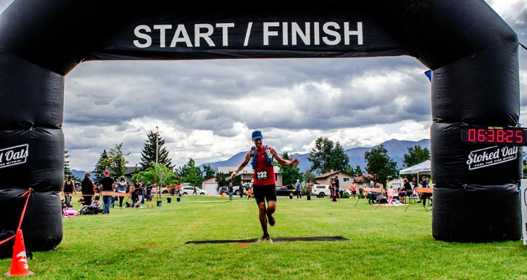 A runner passes through a finish line gateway.