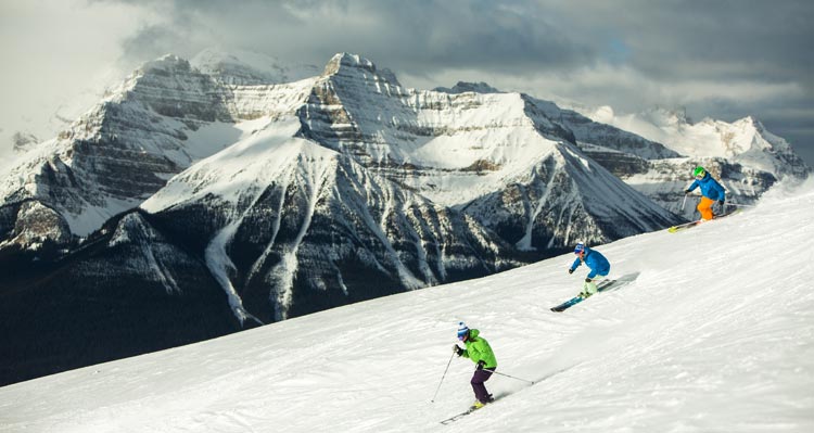 Three people ski down a snowy mountain