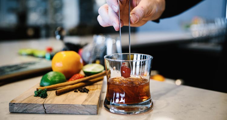 A bartender puts the finishing touches on a whisky cocktail