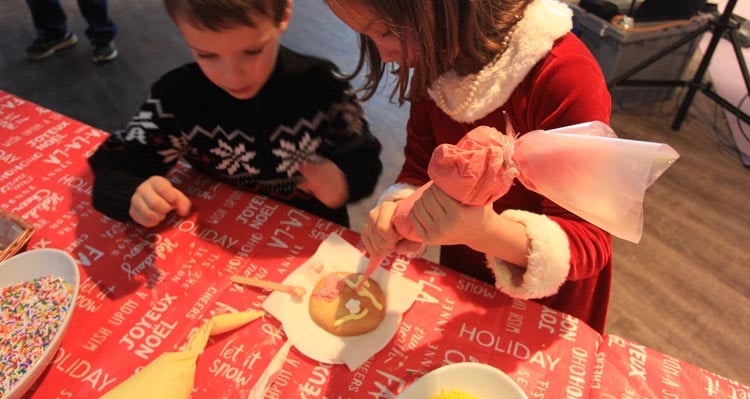 Two children decorate a cookie with icing