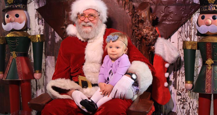 A child sits on Santa's lap in a decorated workshop