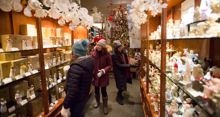 People walk through a shop of Christmas decorations.