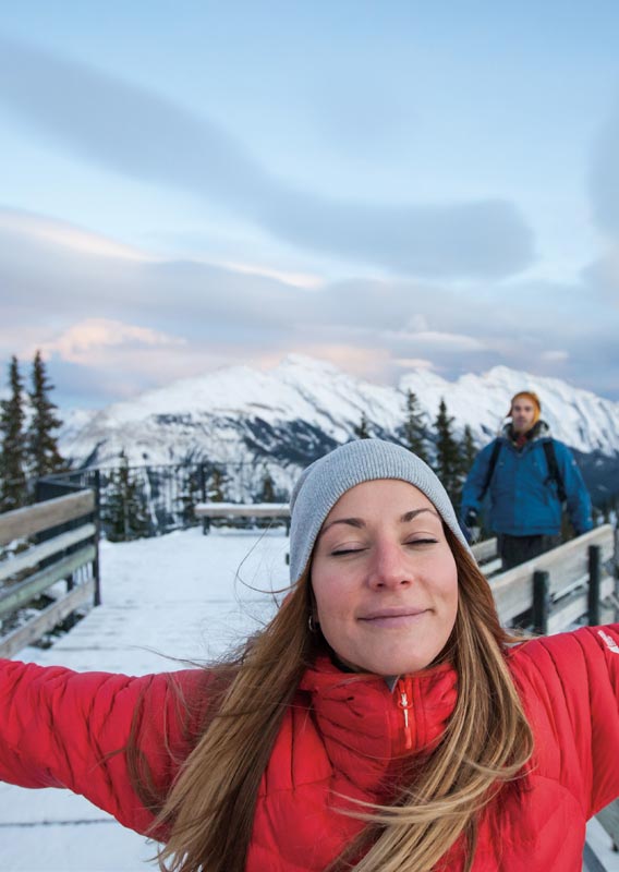 A woman spreads her arms wide on the Sulphur Mountain boardwalk