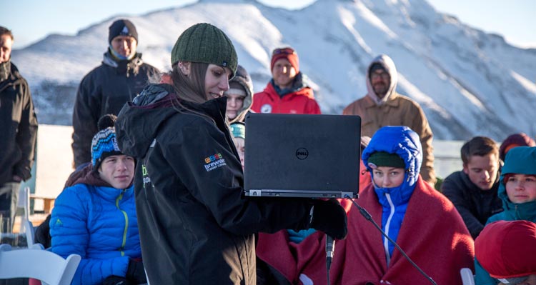 An interpretive guide presents to a group of students with a computer.