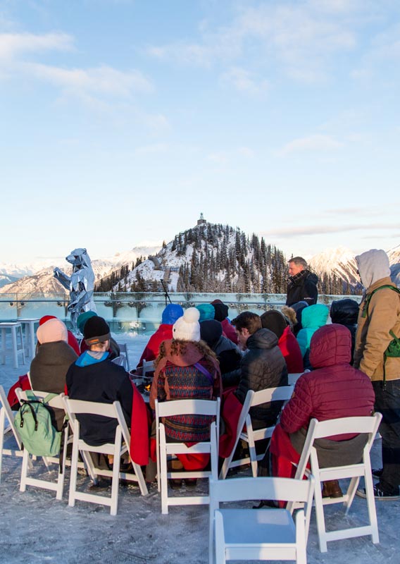 A group of students sit on the upper balcony of the Banff Gondola.