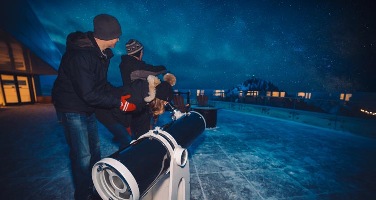 Two people look through a telescope.