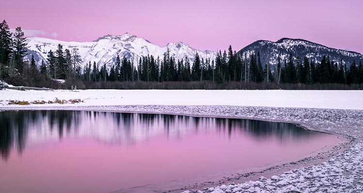Pink sky over snow-covered mountains.