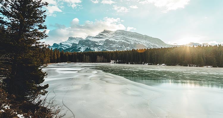 A view of mountains behind a frozen lake and forest