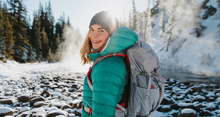 A woman wears a teal jacket in a wintry canyon.