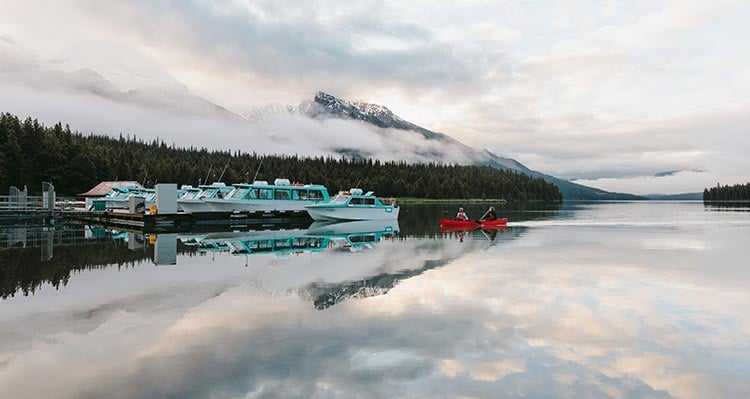 Blue and white boats sit at a dock on a mountainside lake.