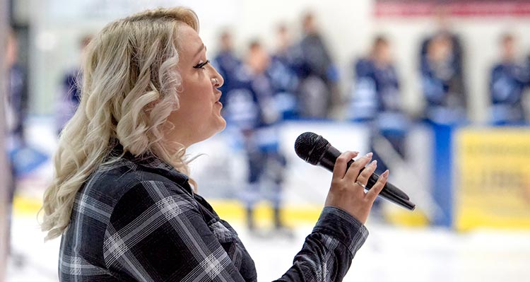 A woman sings at a hockey game.