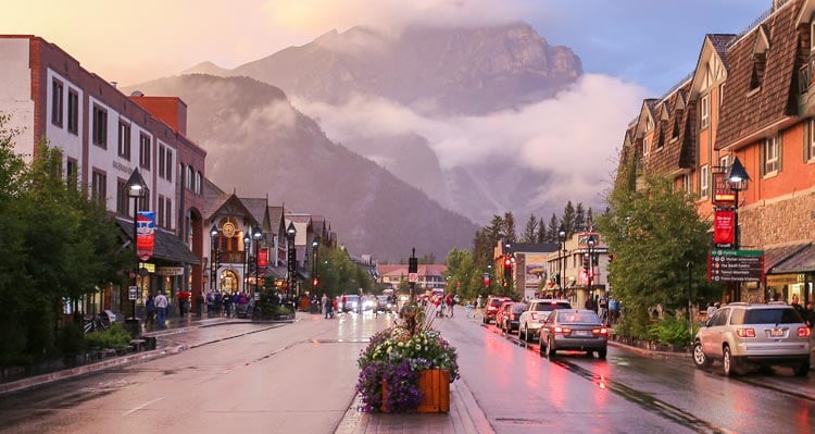 A view down a street toward a tall cloud-covered mountain.