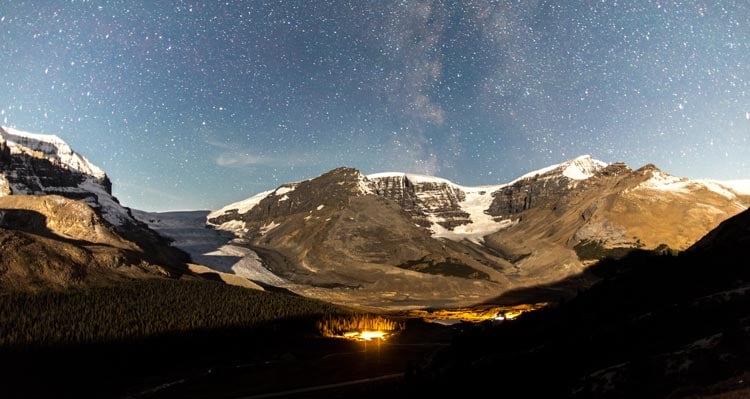 The starry night sky above snow-covered mountains.