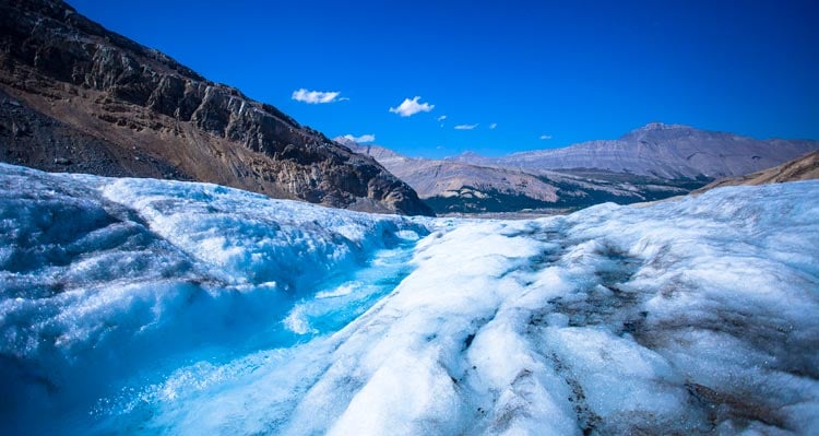 A glacier stretches out from a rocky moraine.